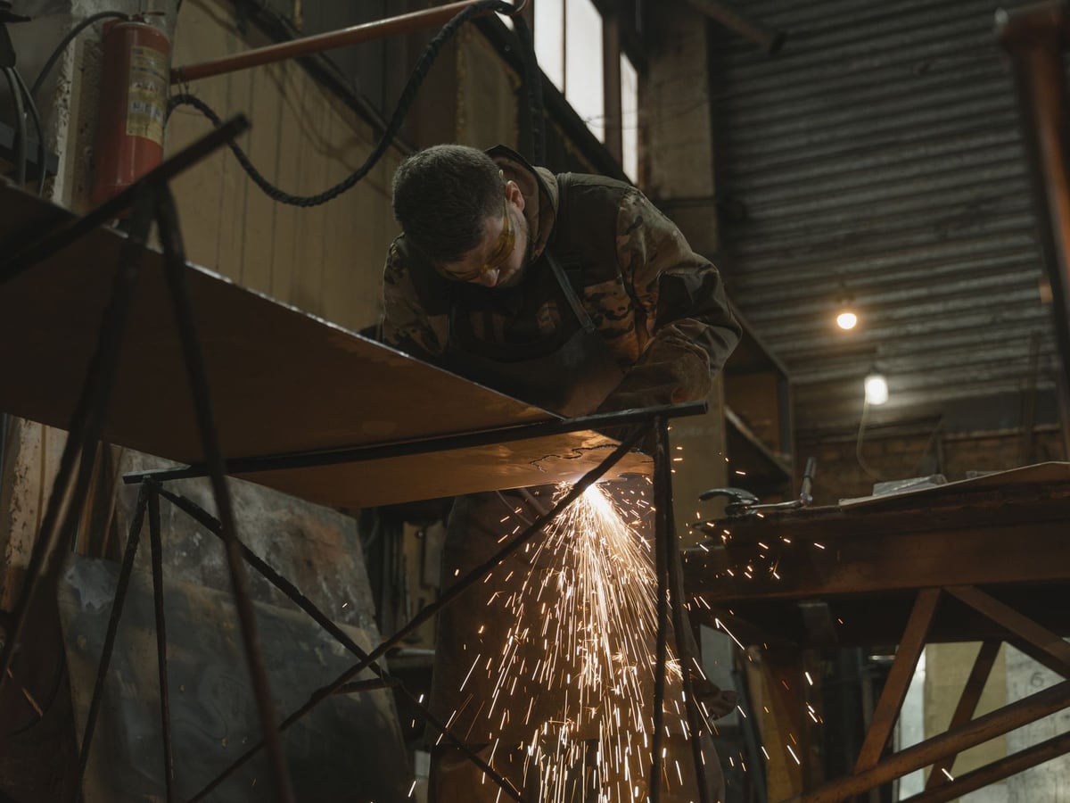 An angle grinder throwing a fan of sparks off a welded steel frame — representative imagery, not a specific Late Night Fabrication job