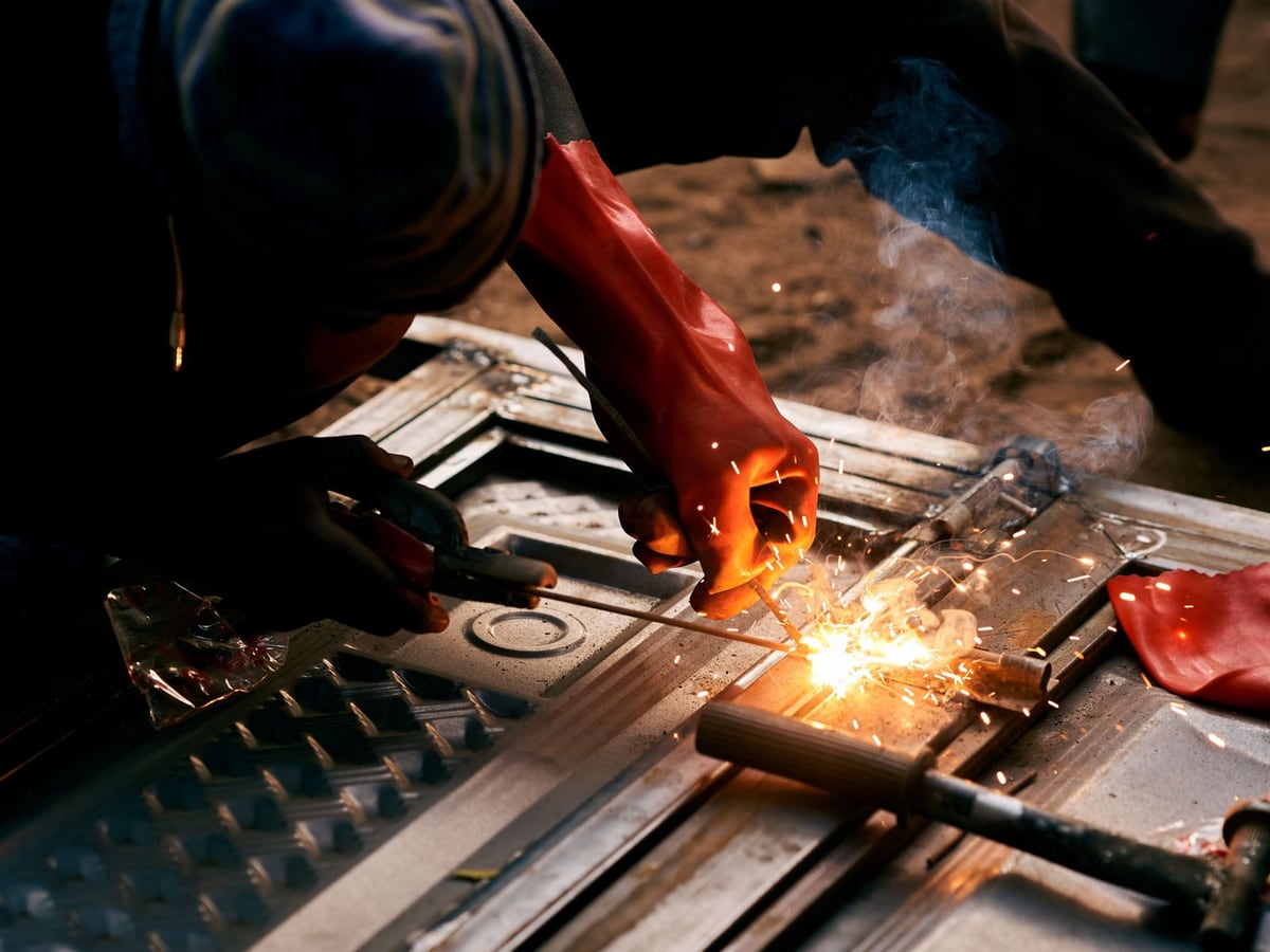 A cutting torch burning along steel stock clamped on a workbench — representative imagery, not a specific Late Night Fabrication job