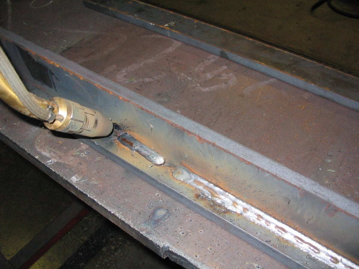 A close view of a finished fillet weld seam joining two steel plates, heat tint along the bead — representative imagery, not a specific Late Night Fabrication job