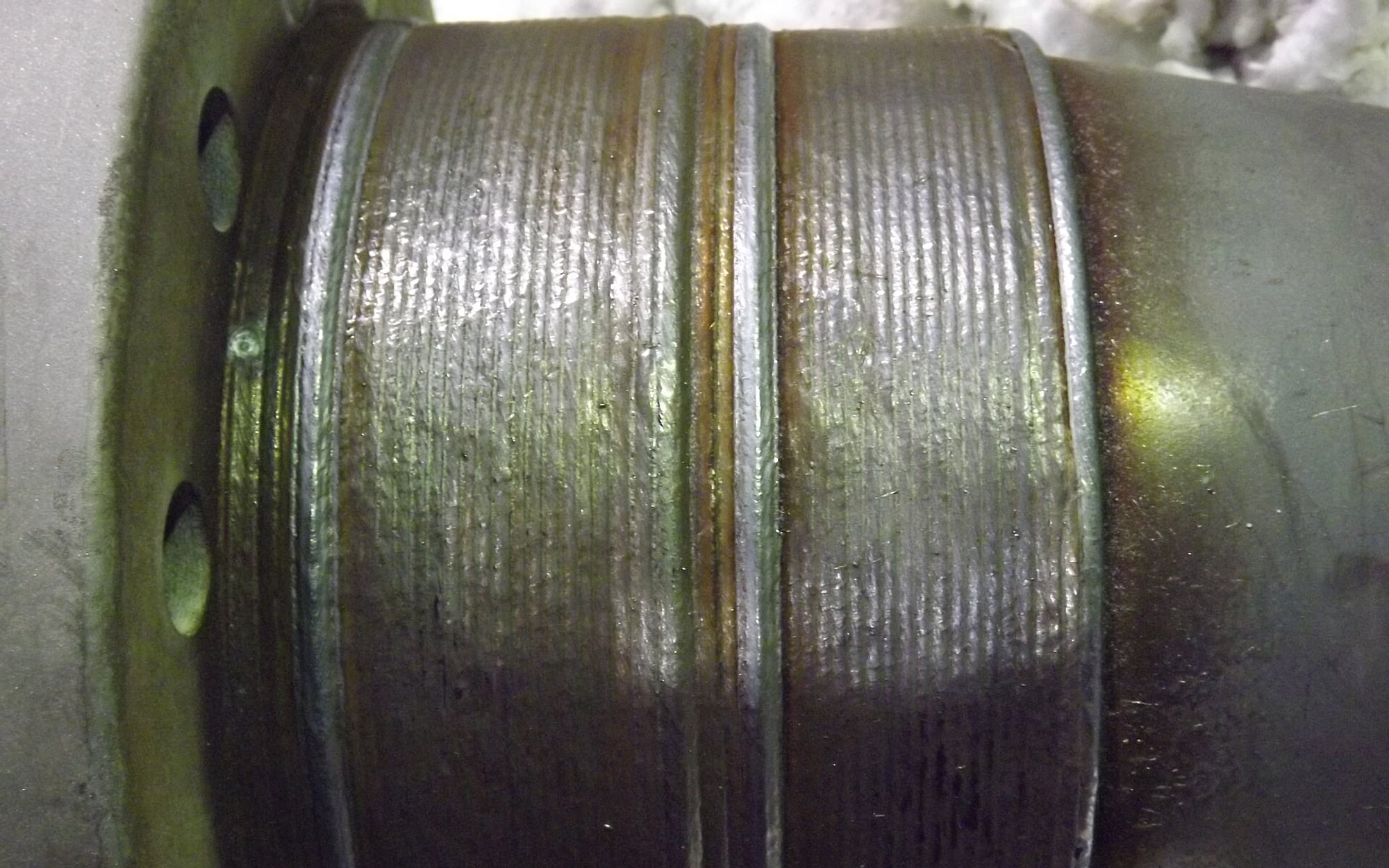 A macro photograph of stacked weld beads running around a welded steel pipe joint — representative imagery, not a specific Late Night Fabrication job